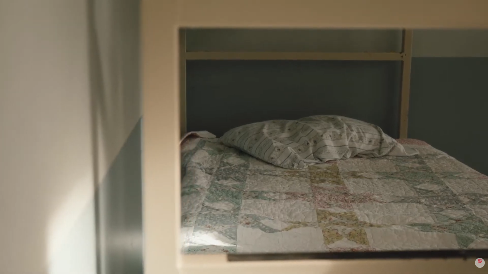 A simple, private sleeping area with a made bed inside the Salvation Army emergency shelter.