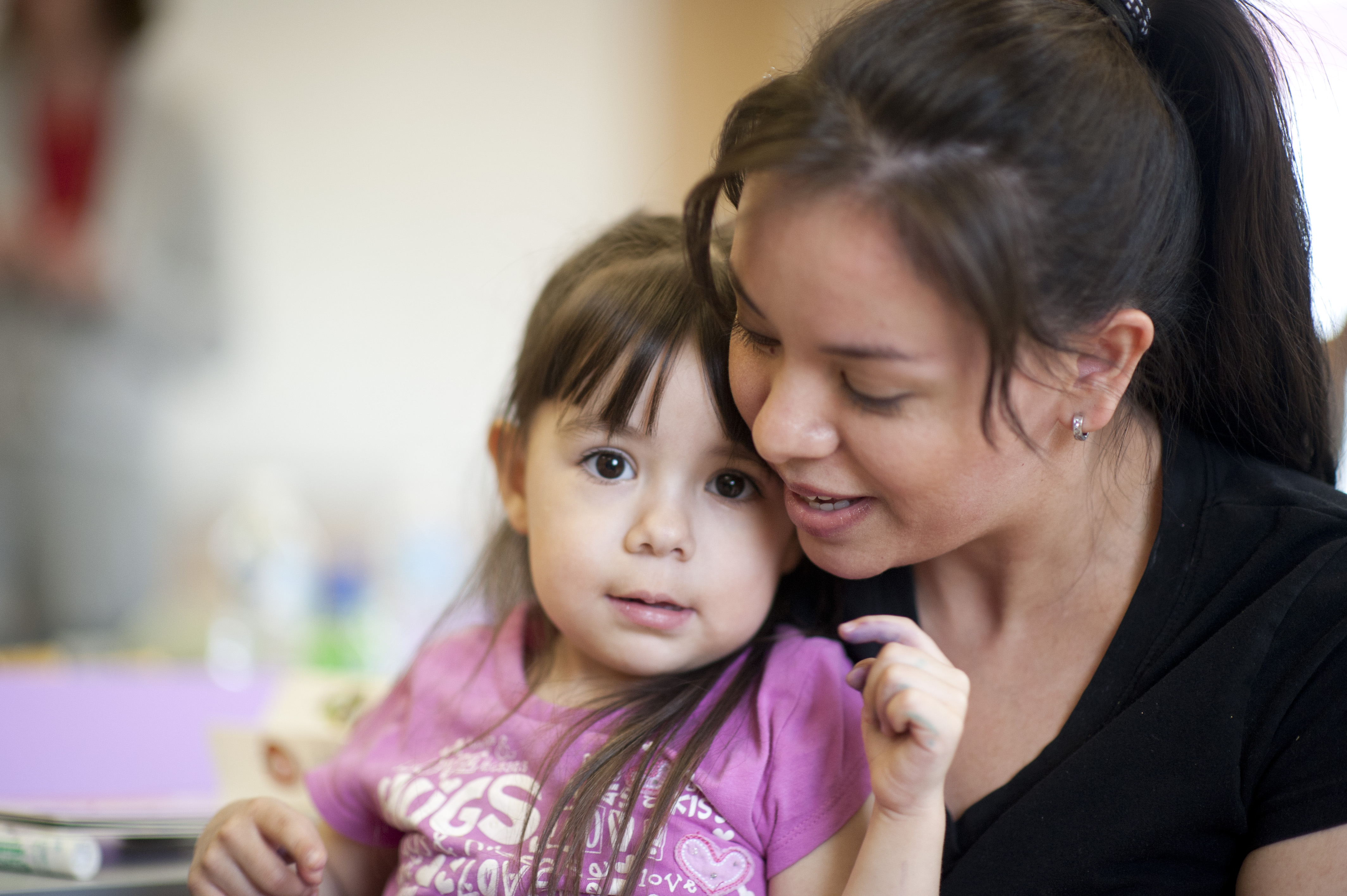 Mother gently holding a young child, showing care, comfort, and support.