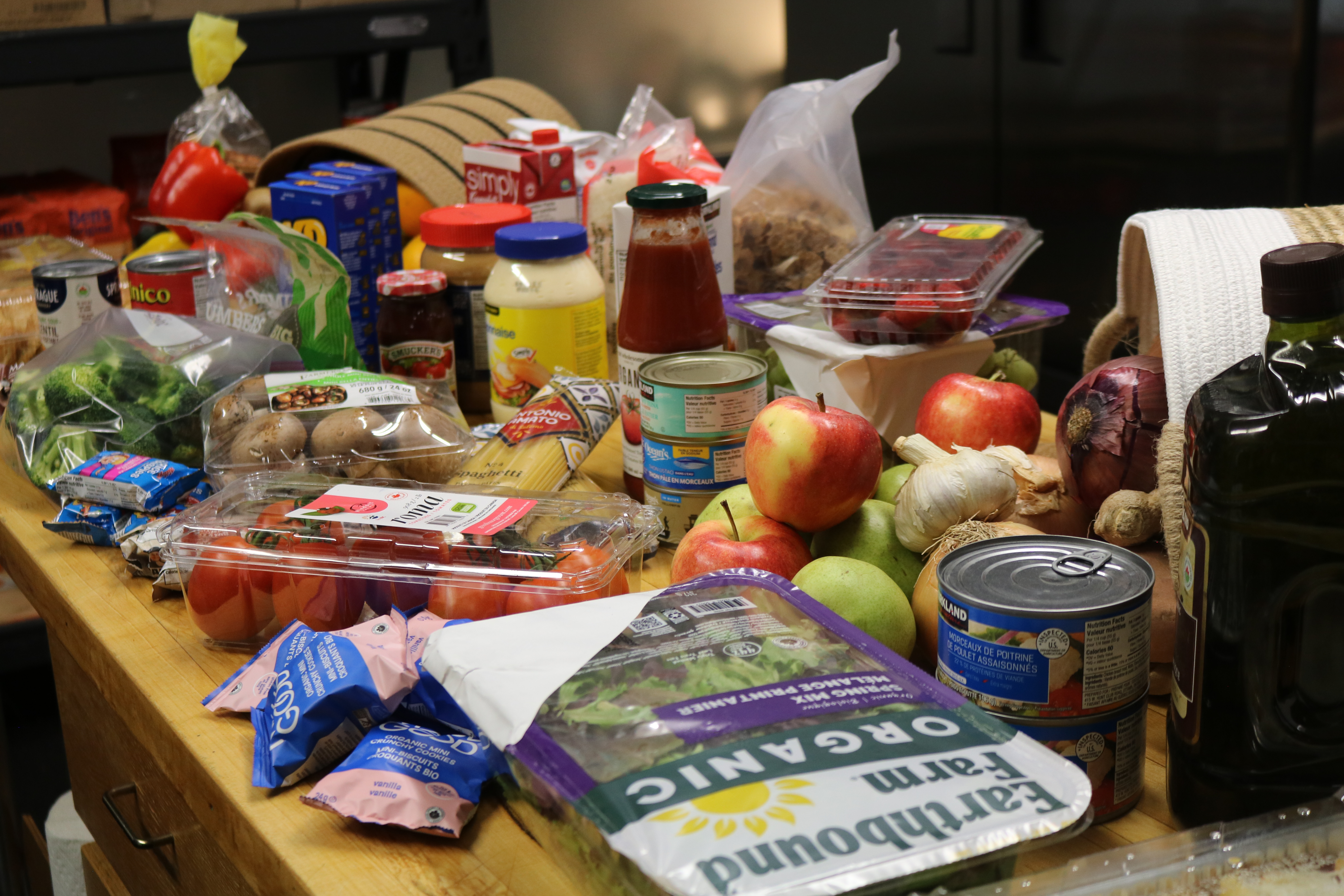 Table filled with emergency food hamper items, including fresh produce, packaged groceries, and pantry staples prepared for community support.
